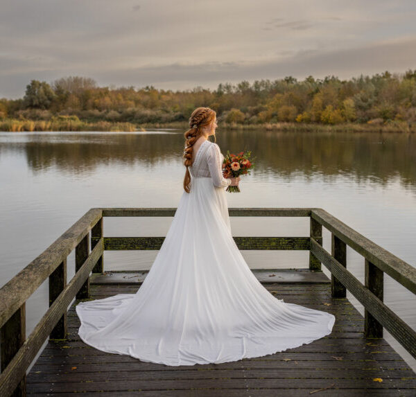 Geklede trouwjurk van The New Bride met lange sleep, gedragen door een bruid buiten